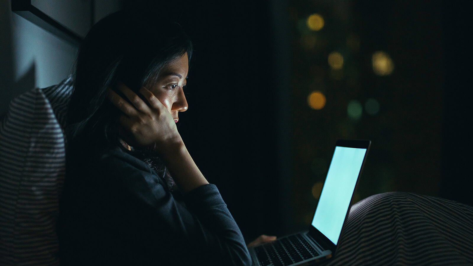Southern Cross - A woman in bed at night while on her laptop A woman in bed at night while on her laptop